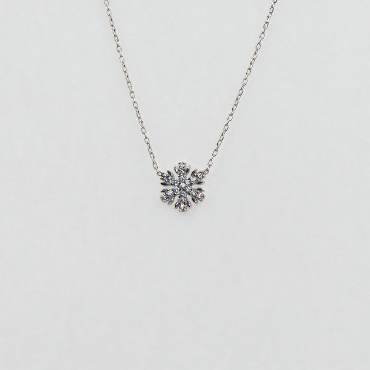 Dieses zierliche 925 Silber Collier mit Anhänger präsentiert ein filigranes Schneeflocken-Motiv, das mit funkelnden weißen Zirkonia-Steinen veredelt ist. Trotz seiner kleinen Größe strahlt es eine elegante Schönheit aus und fängt das Licht auf subtile Weise ein. Dieses Collier ist das perfekte Accessoire für diejenigen, die einen dezenten, aber dennoch glanzvollen Schmuck suchen.
