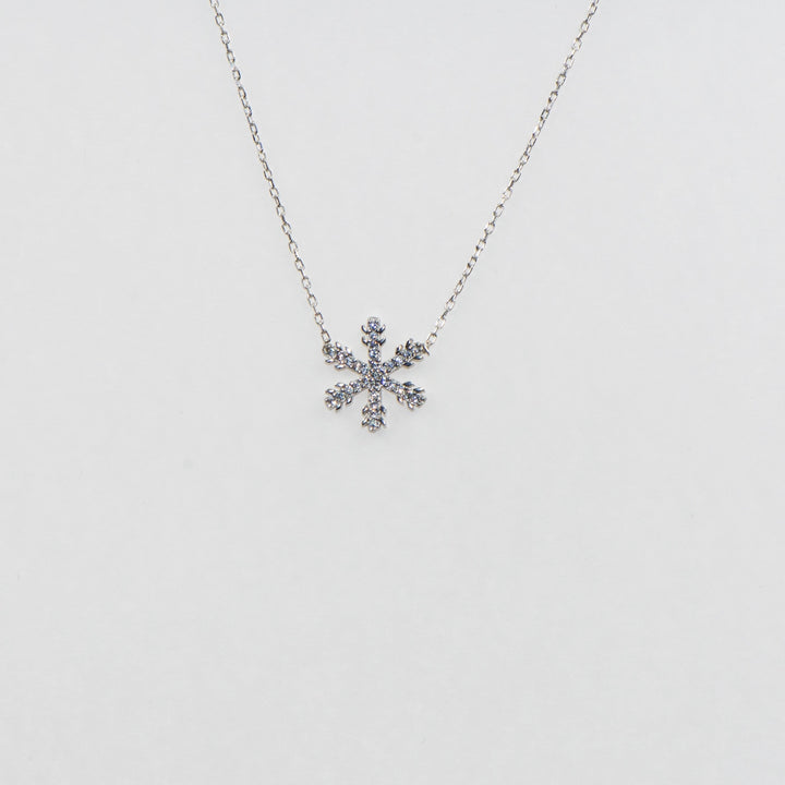 Dieses strahlende 925 Silber Collier mit Anhänger besticht durch ein elegantes Schneeflocken-Motiv, das mit funkelnden weißen Zirkonia-Steinen verziert ist. Die schimmernden Steine fangen das Licht perfekt ein und verleihen diesem Collier eine glanzvolle Ausstrahlung. Mit seiner filigranen Verarbeitung und seinem winterlichen Charme ist es das ideale Accessoire für festliche Anlässe oder als bezauberndes Geschenk.